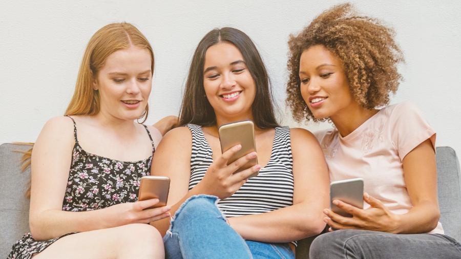 Grupo de mulheres jovens usando celular smartphone grupos de whatsapp - Getty Images