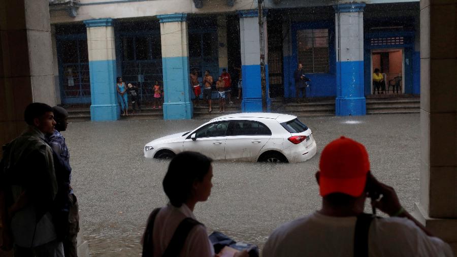 03.jun.22 - Pessoas se protegem da chuva forte ao lado de um carro quebrado em Havana, Cuba - ALEXANDRE MENEGHINI/REUTERS