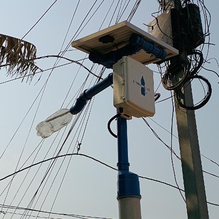 Poste da Litros de Luz na ocupação Anchieta, na zona sul de São Paulo. Ele é feito de cano de PVC e conta com uma bateria de chumbo, uma placa solar, uma lâmpada e uma garrafa PET que ajuda a irradiar a luz