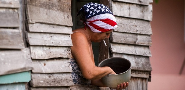 Mulher realiza trabalhos domésticos usando lenço com a estampa da bandeira dos Estados Unidos, em Havana, capital cubana. O presidente dos EUA, Barack Obama, anunciou na última quarta-feira (1º) que irá reabrir a embaixada americana em Cuba no dia 20 de julho - Yamil Lage/AFP