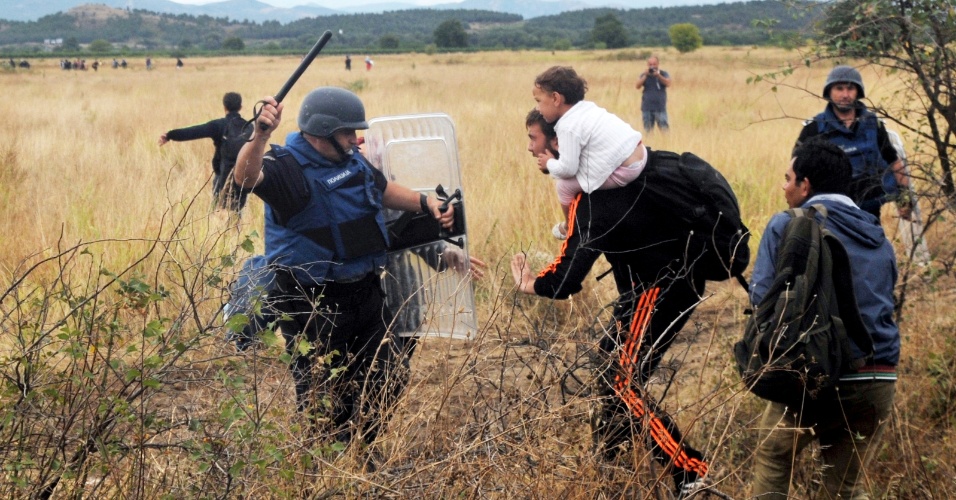 22.ago.2015 - Imigrante tenta passar por policial para entrar na Macedônia, na fronteira com a Grécia. Centenas de pessoas, a maioria refugiados sírios, tentaram entrar no país neste sábado (22)