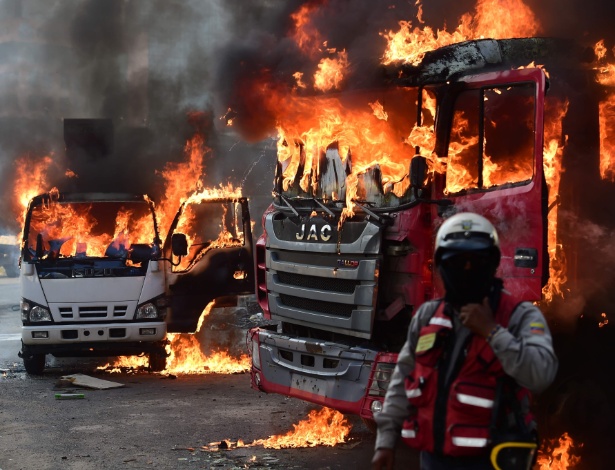 Oficial venezuelano diante de caminhões em chamas durante protesto em Caracas - AFP PHOTO / Ronaldo SCHEMIDT