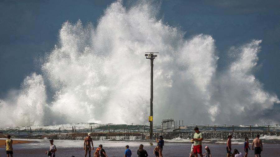 Famílias na praia enquanto onda quebra em piscina de pedra em Sydney em 18 de abril de 2025 Famílias na praia enquanto onda quebra em piscina de pedra em Sydney em 18 de abril de 2025