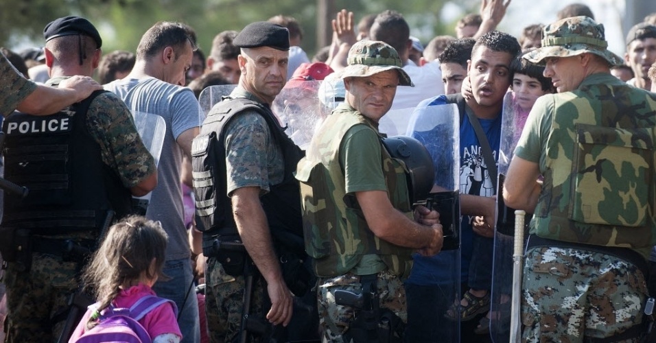 25.ago.2015 - Menina passa por policiais que barram imigrantes na fronteira da Macedônia com a Grécia, perto da cidade de Gevgelija. Durante o fim de semana entraram na Sérvia, pela fronteira com a Macedônia, mais de 7.000 pessoas, principalmente refugiados sírios, informou o Acnur (Agência das Nações Unidas para os Refugiados)