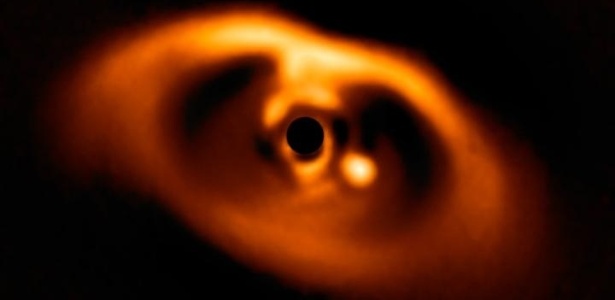 02.julho.2018 - Astrônomos alemães capturaram o exato momento em que um planeta nasce em torno da jovem estrela anã PDS 70. O planeta está visível como um ponto brilhante à direita do centro da imagem - ESO/A. Müller et a