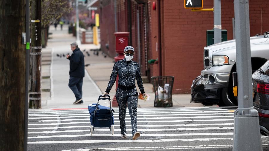 Mulher com máscara carrega carrinho de compras em Nova York, nos Estados Unidos - Johannes EISELE / AFP