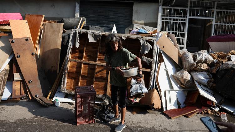 Homem carrega seus pertences após fortes chuvas que atingiram a cidade do Rio