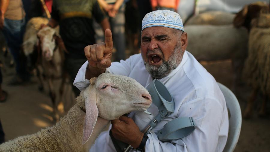 5.ago.2019 - Um palestino gesticula enquanto exibe uma ovelha à venda em um mercado de gado antes do festival de Eid al-Adha, no centro de Gaza - Ibraheem Abu Mustafa/Reuters