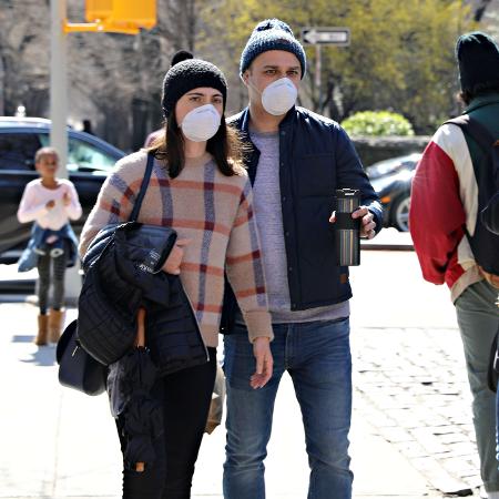 Casal com máscaras de proteção caminha pela 5ª avenida, em Nova York  - Cindy Ord/AFP