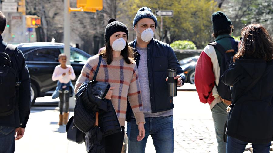 Coronavírus: Casal com máscaras de proteção caminham pela 5ª avenida, em Nova York (EUA) - Cindy Ord/AFP