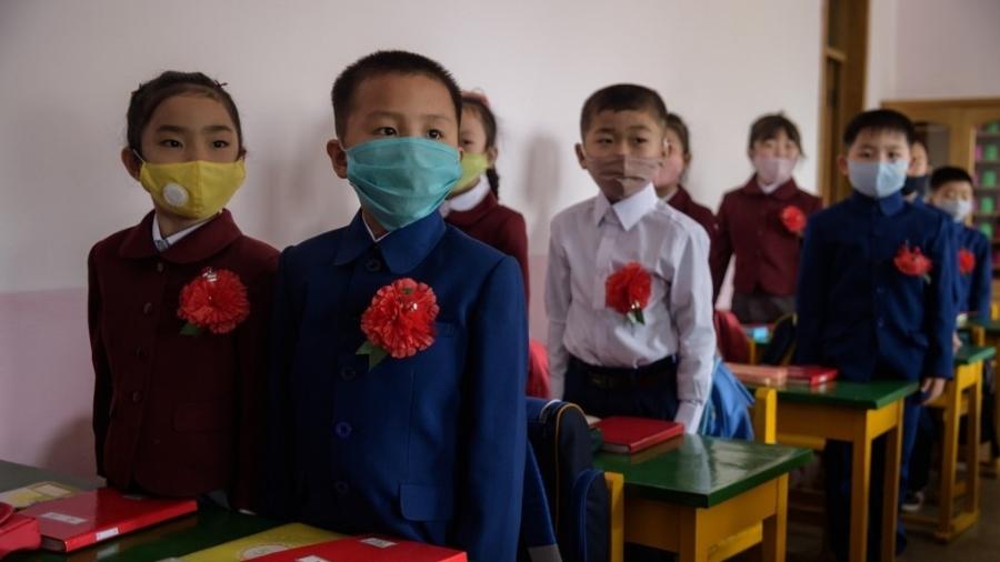 Com máscaras, crianças participam de uma aula na Escola Primária Hasin, no distrito de Sosong, em Pyongyang - KIM Won Jin / AFP