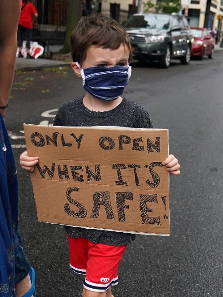 Criança segura cartaz contra reabertura de escolas em Nova York - CARLO ALLEGRI
