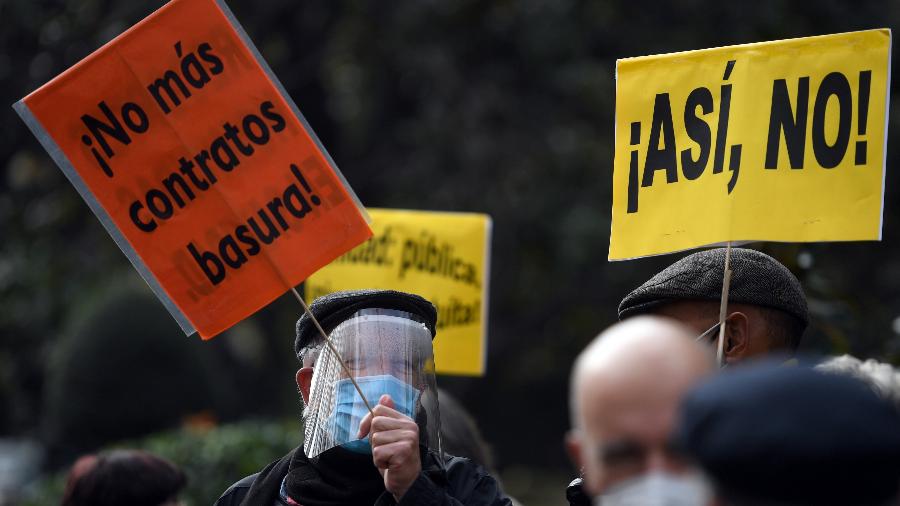 Manifestante segura placa dizendo "chega de contratos precários" durante protesto em Madri - PIERRE-PHILIPPE MARCOU / AFP