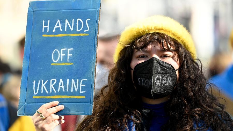 "Tirem as mãos da Ucrânia", pede manifestante. Ela também escreveu "parem a guerra" em sua máscara - Ina Fassbender/AFP