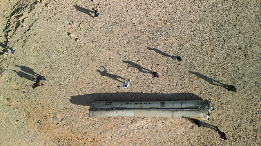 Uma visão de drone mostra pessoas ao redor de restos aparentes de um míssil balístico no deserto, após um ataque do Irã a Israel, perto da cidade de Arad, no sul de Israel