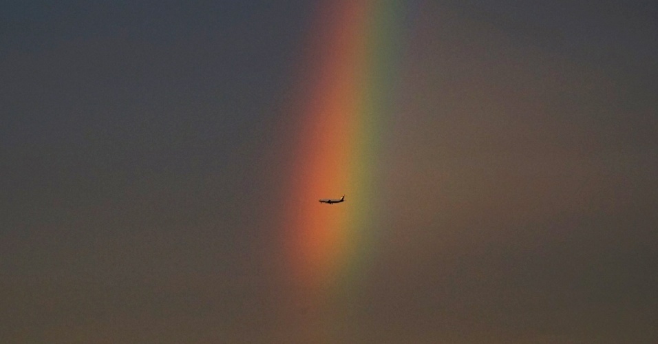 04.ago.2015 - Avião sobrevoa a cidade de Pequim, com arco-íris ao fundo, na China