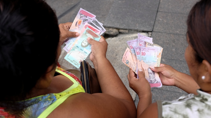 Venezuelanas contam notas de bolívar soberano, a nova moeda do país - Marco Bello/Reuters