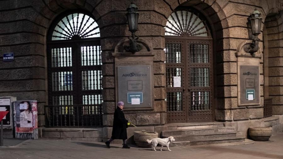 Mulher passeava com seu cachorro durante um toque de recolher imposto para impedir a propagação da doença por coronavírus em Belgrado. - Reuters