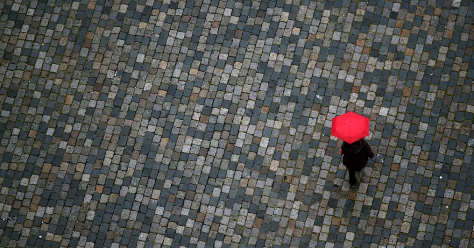 20.out.2015 - Pessoa caminha com guarda-chuva vermelho, em dia chuvoso, nas ruas de Dresden (Alemanha)