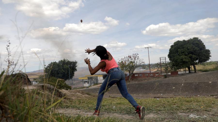 24.fev.19 - De Pacaraima, mulher joga pedra em direção ao lado venezuelano da fronteira; venezuelanos não foram foram incluídos na pesquisa por não serem considerados refugiados  - Ricardo Moraes/Reuters