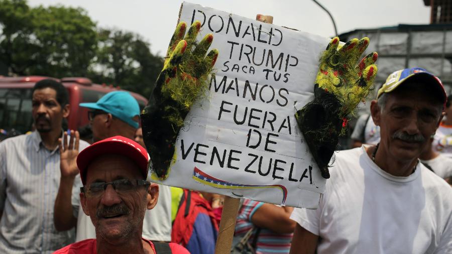 30.03.2019 - Apoiadores de Maduro levam cartaz que diz "Donald Trump, tire suas mãos da Venezuela" - Cristian Hernandez/AFP