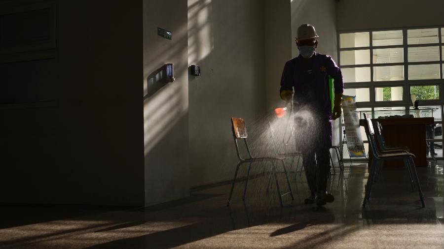 Funcionário joga desinfetante em sala de aula na Indonésia - CHAIDEER MAHYUDDIN/AFP