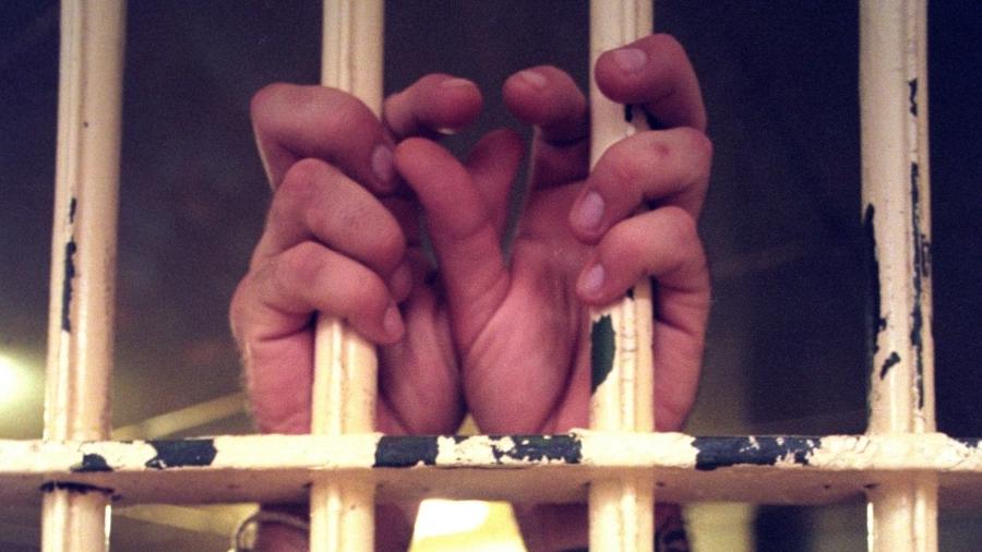 Prisioneiro segura barras em cela - Getty Images