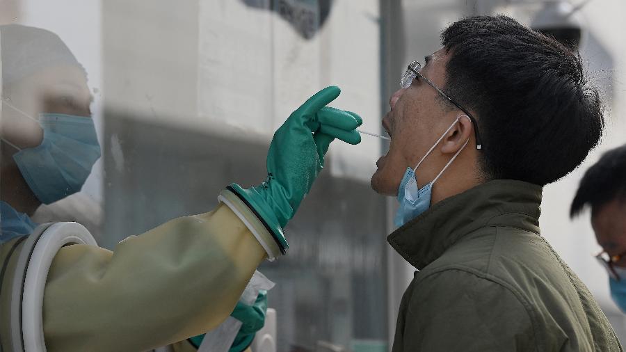 Trabalhador de saúde coleta uma amostra de homem para testar o coronavírus em uma estação em Pequim  - Noel Celis/AFP