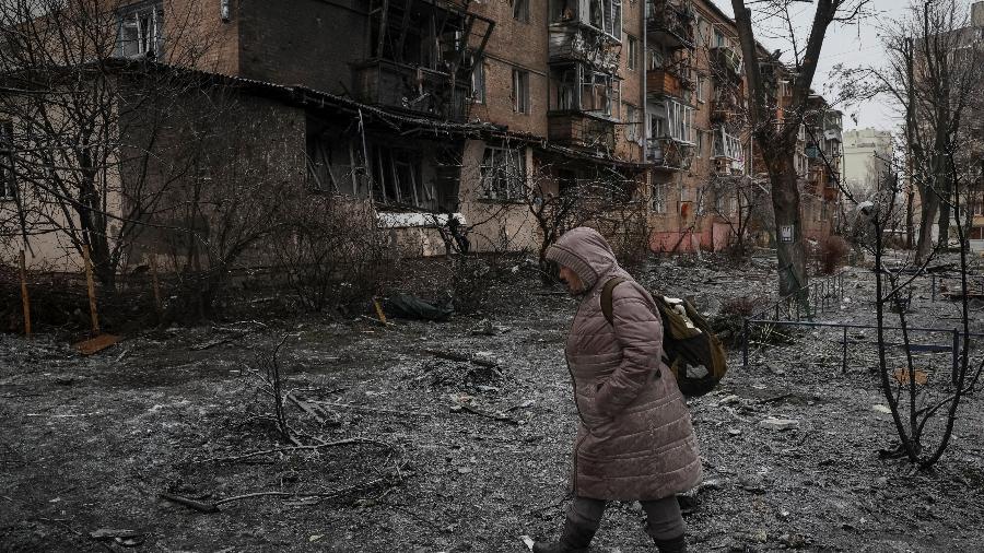 Mulher passa por prédio residencial destruído durante ataque de míssil da Rússia em Vyshhorod, perto de Kiev, capital ucraniana