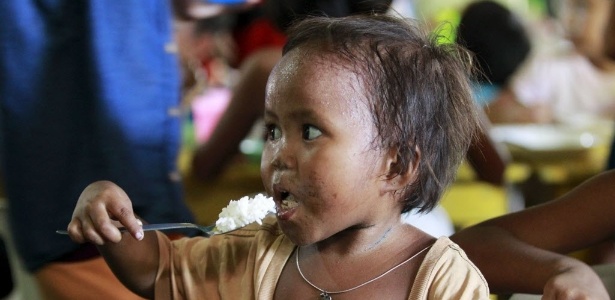 Menino come refeição distribuída durante um programa social de alimentação em favela na cidade de Tondo, nas Filipinas - Romeo Ranoco/Reuters