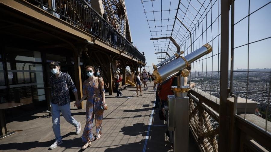 Visitantes passeiam pela Torre Eiffel, em Paris, reaberta ao público em 25 de junho, após três meses de fechamento pela pandemia - Thomas Samson/AFP