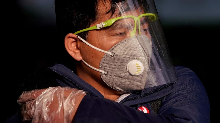 12.fev.2020 - Chinês usa máscara e proteção plástica para evitar contágio pelo coronavírus, em Xangai - Aly Song/REUTERS