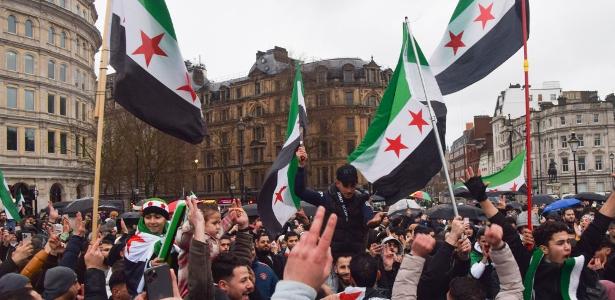 Sírios celebram, em Londres, queda do regime de Bashar al-Assad com bandeiras dos rebeldes