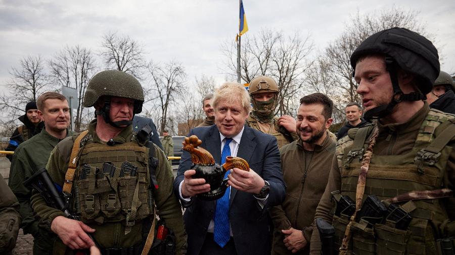 O primeiro-ministro britânico, Boris Johnson, segura um galo de cerâmica que recebeu durante sua visita a Kiev; na foto, ele aparece ao lado do presidente da Ucrânia, Volodymyr Zelensky (sem capacete) - 9.abr.2022 - Presidência da Ucrânia/Reuters