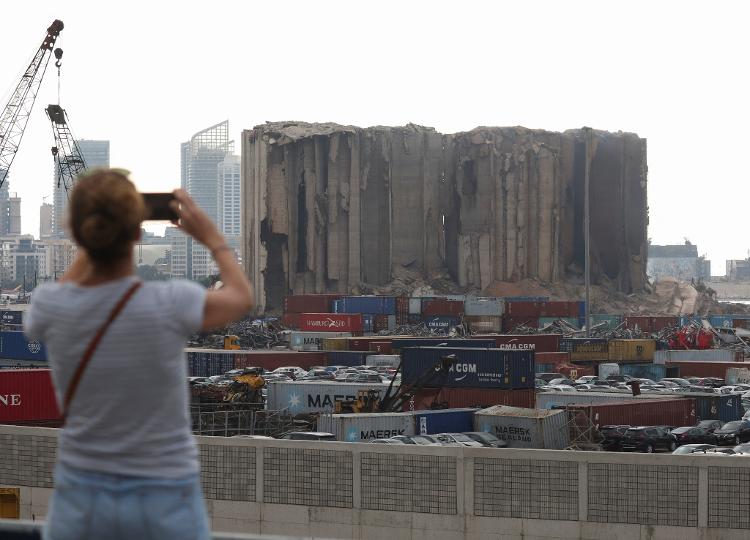 Jul 31.22 - A woman uses her phone near Beirut grain silos that were damaged and partially collapsed in the port explosion in Beirut, Lebanon in August 2020 - MOHAMED AZAKIR/REUTERS - MOHAMED AZAKIR/REUTERS
