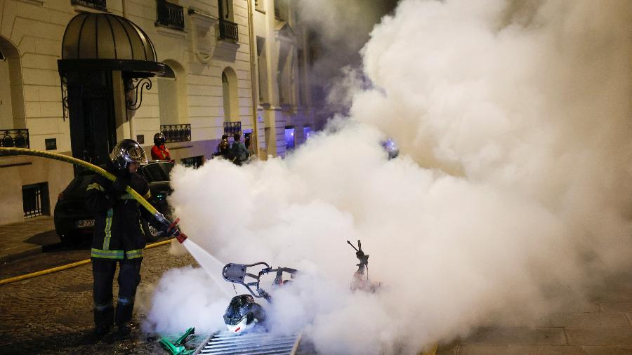 02.jul.23 - Um bombeiro francês trabalha para apagar uma motocicleta em chamas durante o quinto dia de protestos após a morte de Nahel, um adolescente de 17 anos morto por um policial francês em Nanterre durante uma parada de trânsito, em Paris - JUAN MEDINA/REUTERS