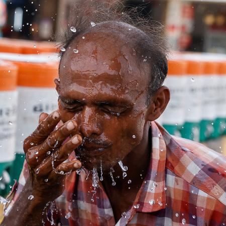 Homem joga água no rosto durante uma onda de calor em Ahmedabad, Índia