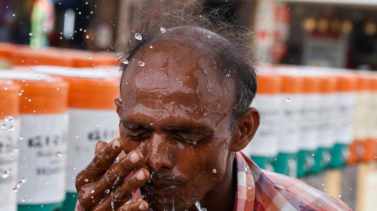 Homem joga água no rosto durante uma onda de calor em Ahmedabad, Índia