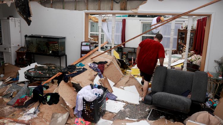 Furacão Milton causa tornados e estragos na Flórida; na imagem, morador anda por casa desmoronada