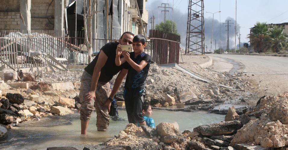 20;ago.2016 - Moradores do bairro de Sheikh Saeed, em Aleppo, na Síria, aproveitam que cano de água estourou e transformam área destruída por bombardeios em área de recreação. A região é dominada por rebeldes