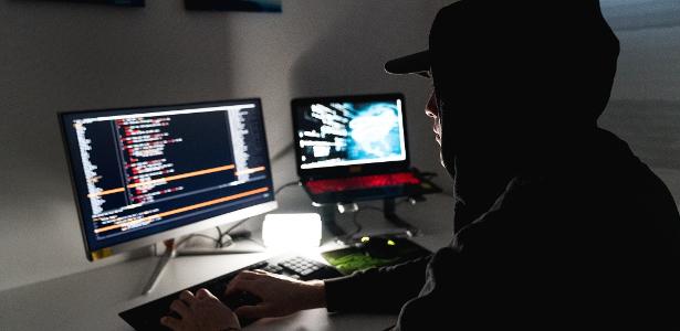 Jovem usando computador para roubar dados; hacker; mundo digital; cibersegurança