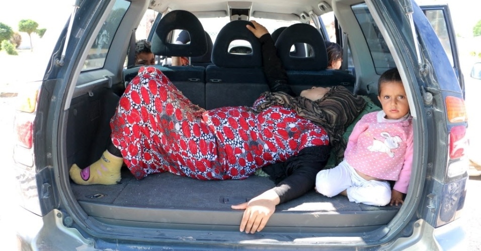 25.jun.2015 - Vítima de combatentes do Estado Islâmico aguarda para cruzar a fronteira para a Turquia, na cidade síria de Tel Abyad. Segundo a televisão estatal síria, os jihadistas atacaram a cidade fronteiriça predominantemente curda de Kobani