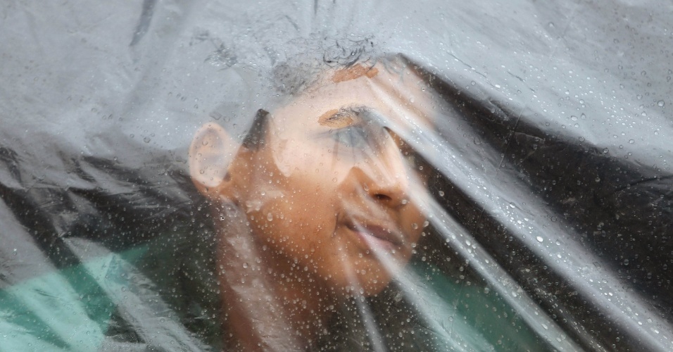 17.nov.2015 - Menino palestino olha através de uma capa de plástico que cobre a casa da sua família, em dia chuvoso em Khan Younis, na faixa de Gaza