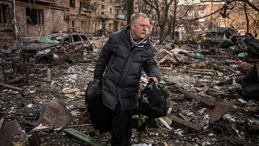 Homem deixa o distrito de Podilsky, em Kiev, na Ucrânia, destruído por um bombardeio russo nesta sexta (18) - André Liohn/UOL