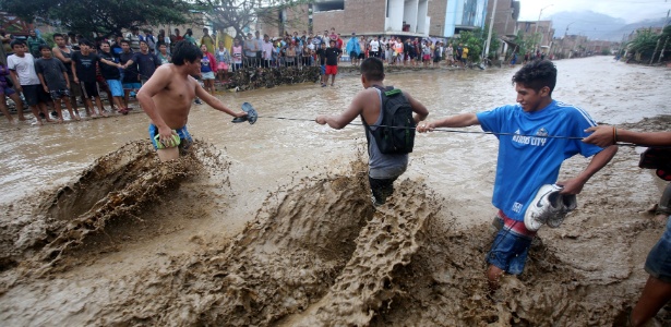 Moradores tentam atravessar rua inundada em Trujillo, no norte do Peru - Douglas Juarez/Reuters