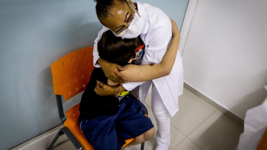 A técnica em enfermagem Maria Rosimeire de Sousa é abraçada por uma criança após aplicação da vacina em Osasco (SP) - ALOISIO MAURICIO/FOTOARENA/FOTOARENA/ESTADÃO CONTEÚDO