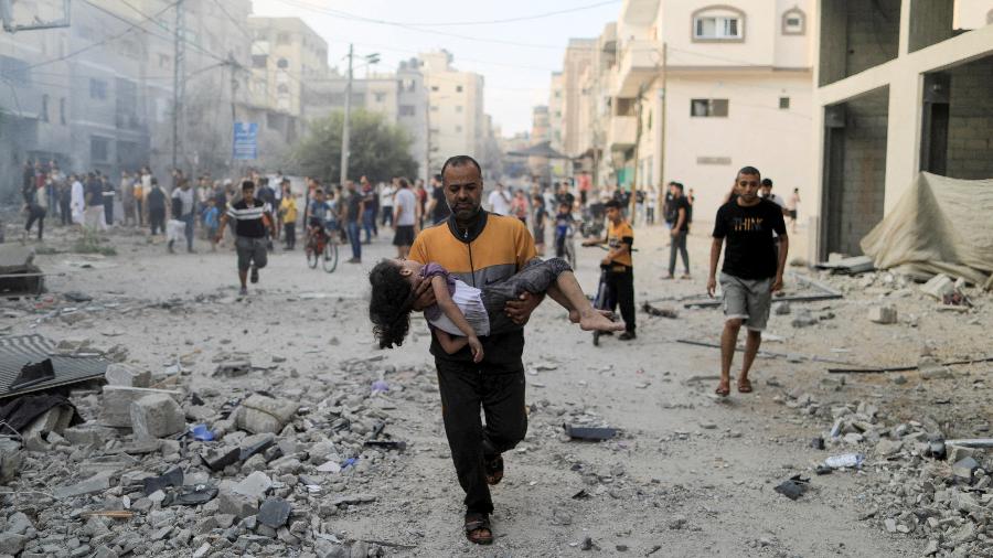 Palestino carrega menina ferida em bombardeio de Israel em Khan Younis, no Sul da Faixa de Gaza