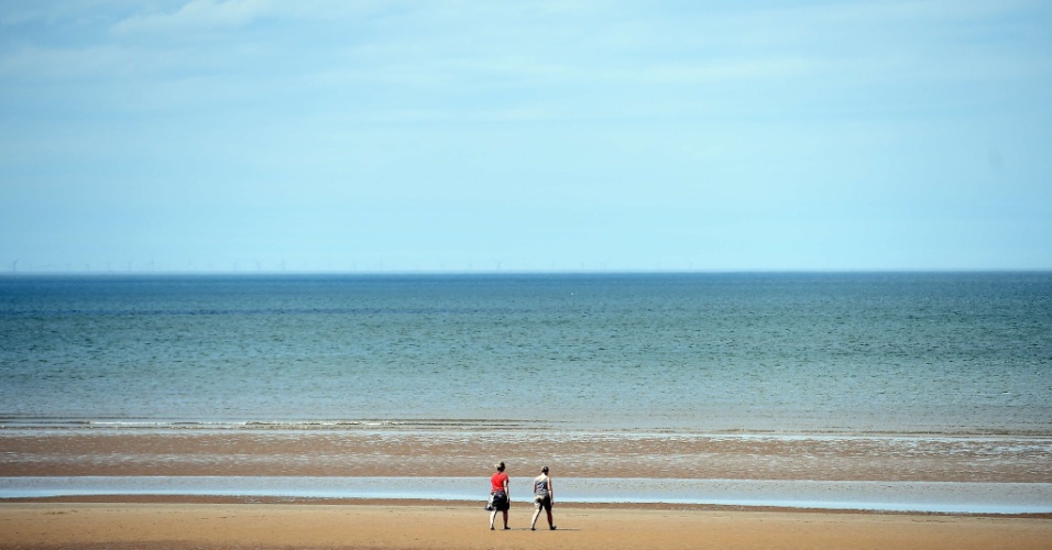 30.jun.2015 - Pessoas caminham na praia de New Brighton, numa tarde com altas temperaturas, na Inglaterra