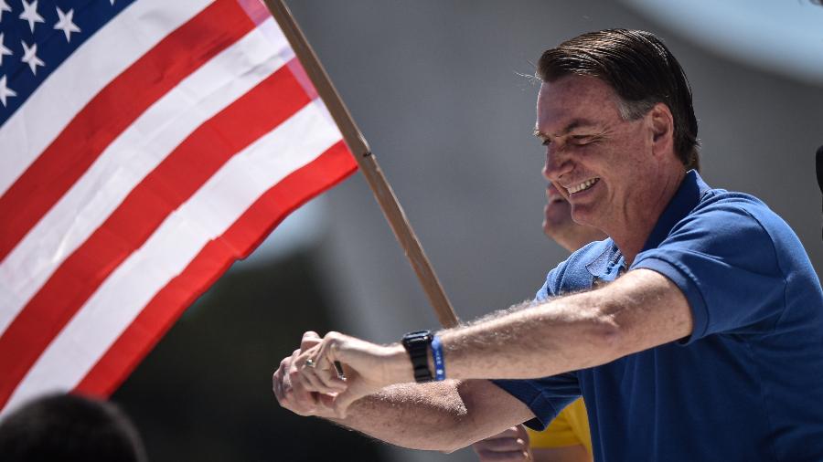 O presidente Jair Bolsonaro cumprimenta apoiadores diante da bandeira dos Estados Unidos - Andre Borges/NurPhoto via Getty Images