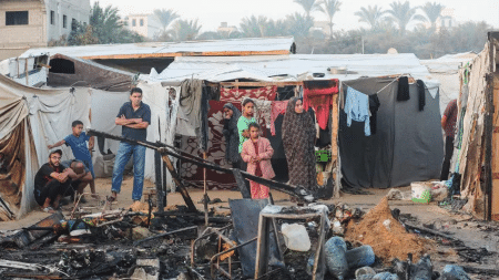 Palestinos em frente a suas tendas carbonizadas 